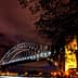 Sydney Harbour Bridge illuminated at night with a clear sky and clouds in the background. - Olive Oil Times