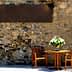 A wooden table with two chairs and a vase of flowers on a stone wall background. - Olive Oil Times