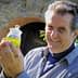 Man smiling while holding a small jar of green olive oil in his hand. - Olive Oil Times