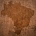 Silhouette map of Brazil displayed on a textured, cracked brown background. - Olive Oil Times
