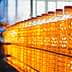 A row of clear plastic bottles filled with yellow cooking oil on a production line. - Olive Oil Times