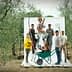 Group of six individuals posing with various gardening tools in an olive grove setting. - Olive Oil Times