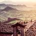 View of rooftops with a mountainous landscape in the background during sunset. - Olive Oil Times