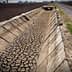 Cracked dry irrigation canal running alongside a gravel road in an agricultural area. - Olive Oil Times
