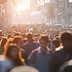 A large crowd of people walking in a busy urban street during sunset with sunlight filtering through. - Olive Oil Times