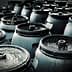 A group of dark storage barrels arranged closely together, showing their tops and lids. - Olive Oil Times