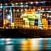 Cargo ship docked at a port, loaded with colorful shipping containers at night. - Olive Oil Times
