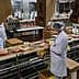 Workers in white coats and hairnets processing meat products on a conveyor belt in a facility. - Olive Oil Times