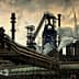 Industrial steel mill featuring large smoke stacks and pipes with visible emissions. - Olive Oil Times