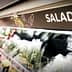 Sign labeled 'SALAD' in a grocery store aisle with various salad ingredients visible. - Olive Oil Times