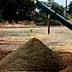 A pyramid-shaped mound of soil on a construction site with machinery in the background. - Olive Oil Times