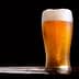 A glass of beer with foam on top, featuring condensation on the outside. - Olive Oil Times