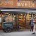 Shopfront of Le Comptoir de Mathilde featuring a chocolatier display and a bicycle cart. - Olive Oil Times