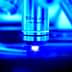 Close-up of a microscope objective lens labeled 100x with a blue background. - Olive Oil Times