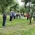 A group of individuals gathered around olive trees in a grove, engaged in discussion. - Olive Oil Times