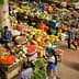 A vibrant market scene filled with various fresh fruits and vegetables on display at stalls. - Olive Oil Times