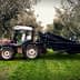 Tractor equipped with olive harvesting equipment parked among olive trees. - Olive Oil Times