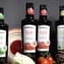 Bottles of Bellucci extra virgin olive oil in various varieties displayed on a table. - Olive Oil Times