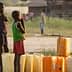 Two children standing beside yellow water containers in an outdoor setting during daylight. - Olive Oil Times