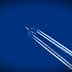An airplane flying high in the sky, leaving behind white contrails against a blue background. - Olive Oil Times