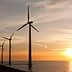 Row of wind turbines along the coastline during sunset with a colorful sky. - Olive Oil Times