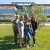 Five individuals standing together outdoors in front of a modern building with greenery. - Olive Oil Times