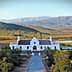 White building of Galenia Estate with mountains and greenery in the background. - Olive Oil Times