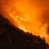 A hillside engulfed in flames during a wildfire, with smoke and orange glow visible. - Olive Oil Times