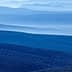 Layered blue mountain landscape featuring rolling hills and valleys in various shades of blue. - Olive Oil Times