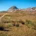 A landscape featuring a hill with a village at its base and dry vegetation in the foreground. - Olive Oil Times