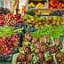 Display of assorted fresh vegetables and fruits including artichokes, green beans, and oranges at a market. - Olive Oil Times