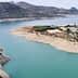 Aerial view of a reservoir with turquoise water and hills in the background. - Olive Oil Times