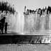 Silhouettes of children playing in a water fountain with water spraying in the background. - Olive Oil Times