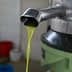 Stream of fresh olive oil flowing from a metal spout during the extraction process. - Olive Oil Times
