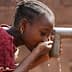 A child drinking water from a tap using cupped hands in a close-up view. - Olive Oil Times