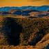 A view of a mountainous landscape featuring rolling hills and vegetation under a sunset sky. - Olive Oil Times