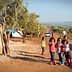 Group of children standing in an olive grove with tents in the background. - Olive Oil Times