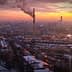 Aerial view of an industrial area with smoke stacks emitting smoke against a sunset sky. - Olive Oil Times