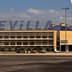Sevilla airport building with the word 'SEVILLA' displayed prominently and a Ryanair airplane wing in the foreground. - Olive Oil Times