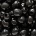 Close-up image of shiny black olives with visible holes. - Olive Oil Times