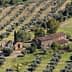Aerial view of a farmhouse surrounded by olive trees in a rural landscape. - Olive Oil Times