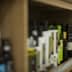 Various bottles of olive oil displayed on wooden shelves in a store. - Olive Oil Times