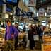 Interior view of a fish market with customers browsing and vendors displaying seafood. - Olive Oil Times