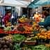 A market stall filled with various fresh fruits and vegetables, including tomatoes, oranges, and leafy greens. - Olive Oil Times