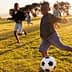 Group of children running and playing soccer on a grassy field during sunset. - Olive Oil Times