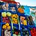 Assorted fresh fruits and vegetables displayed in blue crates at a market by the water. - Olive Oil Times