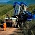 Blue olive harvesting machine positioned on a dirt path in an olive grove. - Olive Oil Times