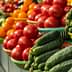 Baskets of cucumbers and tomatoes arranged in a market setting with vibrant colors. - Olive Oil Times
