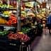 A market aisle filled with various fruits and vegetables displayed on shelves and crates. - Olive Oil Times