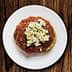 A plate of dakos salad featuring a base of barley rusk topped with tomato sauce and crumbled feta cheese. - Olive Oil Times